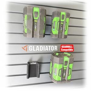 Puede incluir: Cuatro soportes de pared negros PARTFORGE para baterías de herramientas eléctricas. La imagen también muestra baterías de herramientas eléctricas en gris y verde, montadas en una pared de lamas. La palabra "GLADIATOR" es visible.
