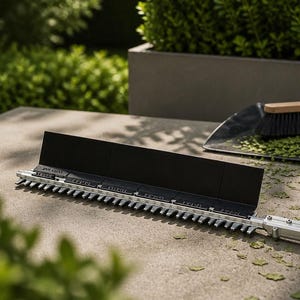 May include: A long, silver-toned hedge trimmer attachment featuring a black blade guard and a green handle grip. Nearby, a black dustpan holds a small wooden-handled brush with black bristles, surrounded by scattered green leaf clippings.