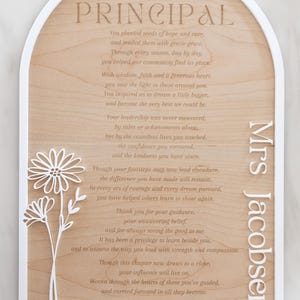 Puede incluir: Una placa de madera arqueada con un marco blanco que presenta el texto PRINCIPAL, un poema y el nombre Mrs Jacobsen. Un recorte floral blanco est&aacute; unido al lado izquierdo. El poema comienza con You planted seeds of hope and care y termina con Love Bree.