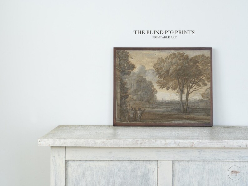 May include: A printable art print depicting a landscape scene with a building in the distance, trees, and figures in the foreground. The print is framed in a brown wood frame and features the text "THE BLIND PIG PRINTS PRINTABLE ART" at the top.