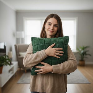 Peut inclure: Un coussin vert tissé de forme rectangulaire. Le coussin présente un motif texturé en forme de panier. Le coussin est d'une nuance de vert profond et semble être fait d'une matière douce. Le coussin est tenu par une personne.