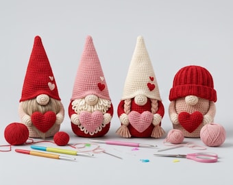 May include: Four handmade crochet gnomes in red, pink, and cream colors, each holding a heart. The gnomes have long, pointed hats and white beards. Crochet hooks, yarn, and scissors are arranged in front of the gnomes, suggesting a crafting theme.
