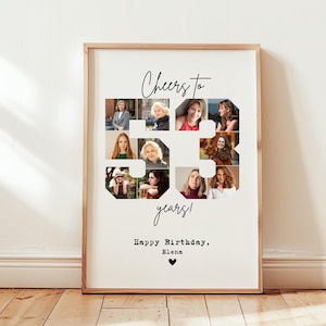 Op de afbeelding: Een ingelijste print met een licht houten frame. De print toont een collage van negen foto's gerangschikt in de vorm van het getal 53. De woorden "Cheers to 53 years!" staan boven de foto's, met "Happy Birthday, Elena" eronder.
