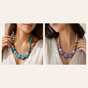 May include: Two necklaces featuring chunky, irregular beads in shades of blue and purple. The blue necklace has turquoise and teal beads with gold-toned spacers. The purple necklace features lavender and violet beads with gold-toned accents.