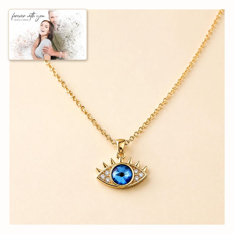 Gold-tone necklace with a blue eye-shaped pendant, catalog view. A personalized greeting-card example appears in the corner.
