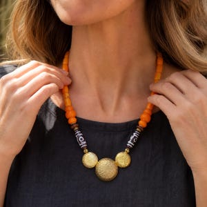 Three-piece handmade necklace set featuring orange and beige beaded necklace, orange and brown beaded necklace and orange and brown beaded necklace, displayed together to show the coordinated colors and beadwork