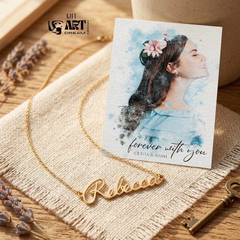 May include: A gold-colored necklace with the name "Rebecca" in cursive script. A card with a watercolor portrait of a woman and the text "forever with you" is next to the necklace. The background includes a key and lavender sprigs.