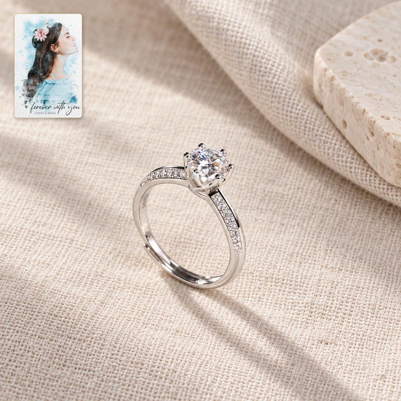 Moissanite Solitaire Ring, laid on fabric. A sample personalized digital greeting card is shown alongside.