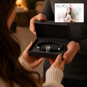 Puede incluir: Una pulsera de cuentas negro mate con un dije de corona plateado con detalles negros, presentada en una caja de regalo negra. Incluye una tarjeta rectangular con una fotograf&iacute;a de una pareja y el texto "forever with you OLIVIA & ADAM."