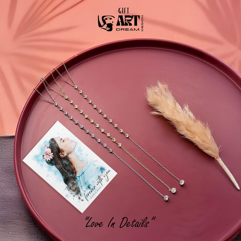 May include: Three delicate necklaces with small, sparkling stones are displayed on a maroon tray, alongside a card with a watercolor illustration of a woman. A dried feathery plant adds a natural touch. The text "Love In Details" is at the bottom.