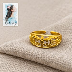 Golden Bloom Filigree Ring arranged on soft ivory linen in a refined neutral flat lay. A personalized digital greeting card is shown alongside.