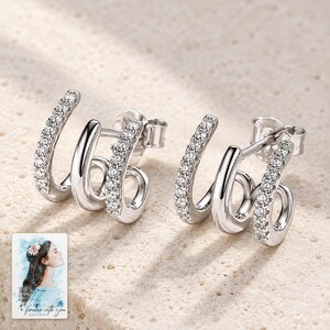Triple Arc Stud Earrings, shown on a display surface. A sample personalized digital greeting card is shown alongside.