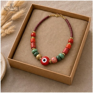 Red Evil Eye Beaded Necklace presented in an open jewelry gift box on natural linen