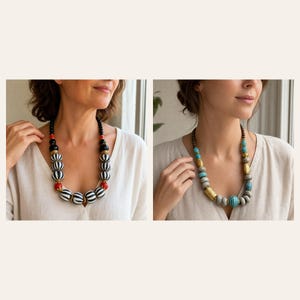 May include: A statement necklace featuring large, round, black and white striped beads accented with smaller red spheres and gold-toned spacers. Beside it, a second necklace displays textured grey, turquoise, and metallic gold-toned cylindrical beads.