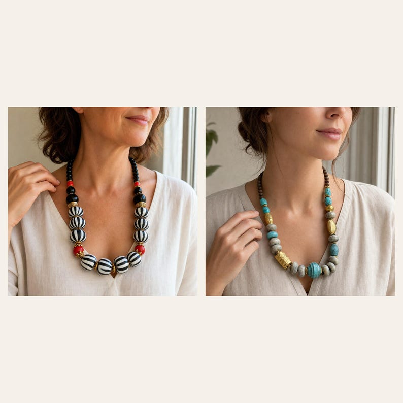 May include: A statement necklace featuring large, round, black and white striped beads accented with smaller red spheres and gold-toned spacers. Beside it, a second necklace displays textured grey, turquoise, and metallic gold-toned cylindrical beads.