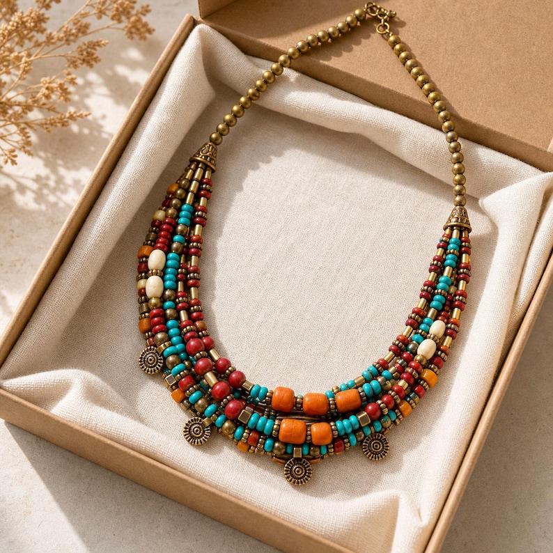 Top down lifestyle view of Multistrand turquoise red orange and antique-brass ethnic necklace on softly textured ivory linen