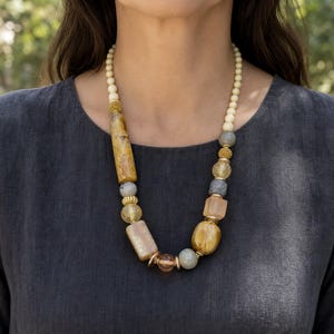 Three-piece handmade necklace set featuring beige and brown beaded necklace, beige and brown beaded necklace and orange and brown beaded necklace, displayed together to show the coordinated colors and beadwork