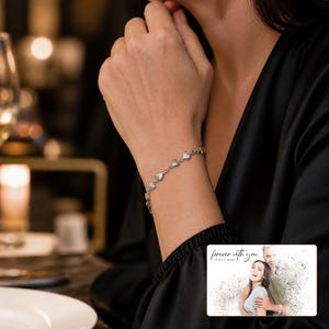 Linked Hearts Steel Bracelet arranged on soft ivory linen in a refined neutral flat lay.