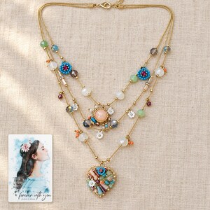 Bohemian Heart Cascade Necklace arranged on soft ivory linen in a refined neutral flat lay. A personalized digital greeting card is shown alongside.