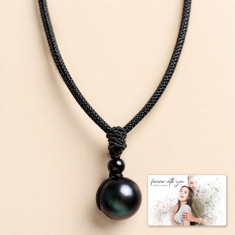 Black cord necklace with a dark round pendant, display view. A personalized greeting-card example appears in the corner.