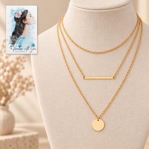 Close view of the necklace trio showing fine oval chain links, the narrow bar with end holes and the smooth circular pendant. A personalized digital greeting card is shown alongside.