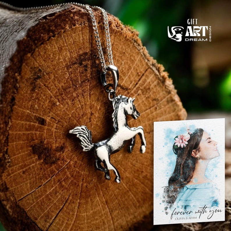 Puede incluir: Un collar con colgante de caballo plateado con un dise&ntilde;o detallado, exhibido sobre una superficie de madera. El colgante presenta un caballo encabritado con crin y cola fluidas. Tambi&eacute;n es visible una impresi&oacute;n de acuarela con el texto "forever with you".