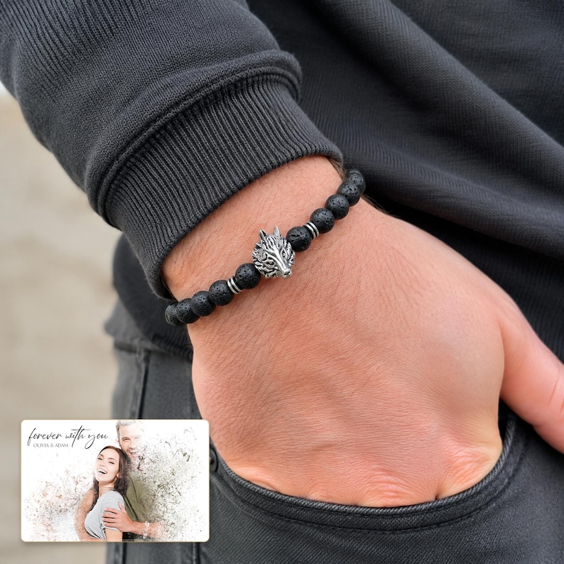 Black bead bracelet with silver-tone wolf-head detail, worn view. A personalized greeting-card example appears in the corner.