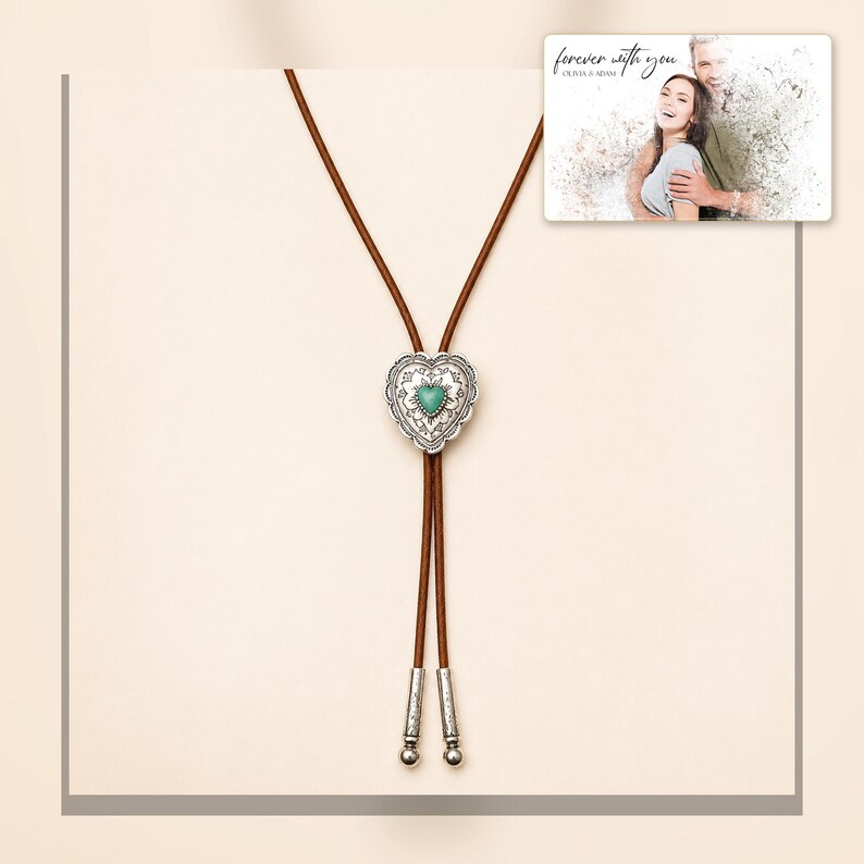 Brown cord bolo necklace with a silver-tone heart slide and turquoise-color center, framed product view. A personalized greeting-card example appears in the corner.