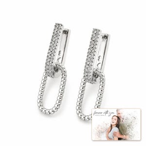 Silver Current Zircon Drops shown during a believable gift-giving moment between adults with the exact jewelry visible.
