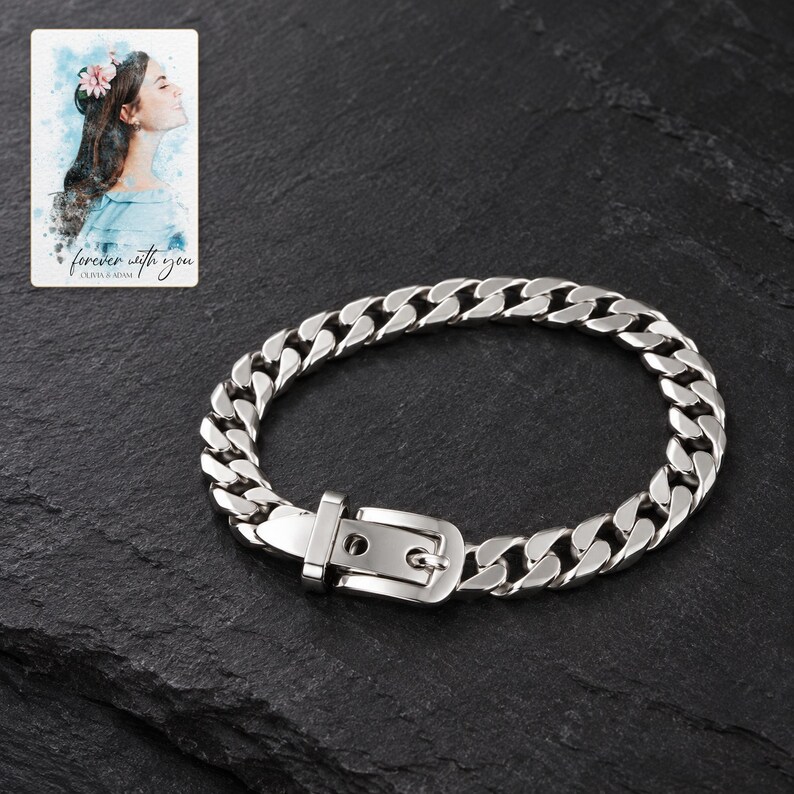 Polished silver tone curb-chain bracelet with belt buckle against dark charcoal slate. A personalized digital greeting card is shown alongside.