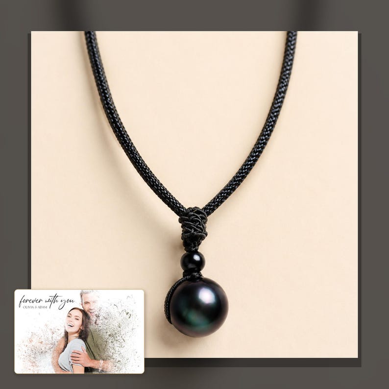 Black cord necklace with a dark round pendant, dark-bordered product view. A personalized greeting-card example appears in the corner.