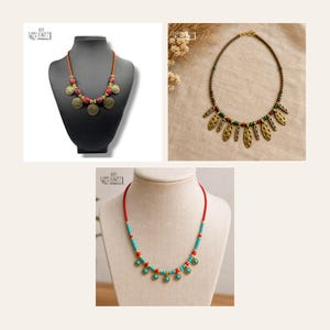 May include: Three necklaces displayed together. One features red beads and gold-toned circular charms on a cord. Another has small green and red beads with gold-toned oval pendants. The third necklace has turquoise and red beads with small charms.