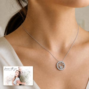 Puede incluir: Un collar de tono plateado con un colgante circular que tiene la palabra HOPE grabada en letras may&uacute;sculas y una peque&ntilde;a piedra en forma de coraz&oacute;n en el centro. El marco circular est&aacute; decorado con peque&ntilde;as piedras claras.