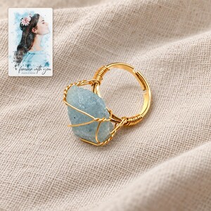 Blue Wire Wrapped Ring, linen flatlay view. A personalized digital greeting card is shown alongside.