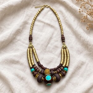 Gift ready presentation of Antique-brass and brown three-strand statement necklace with turquoise-inlaid focal bead in an open jewelry box lined with natural ivory linen