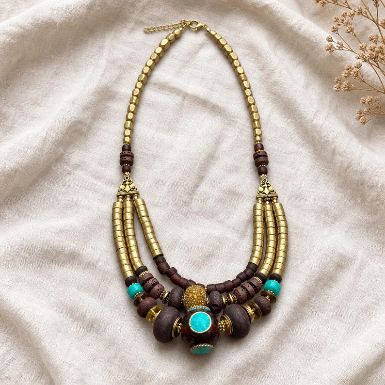 Gift ready presentation of Antique-brass and brown three-strand statement necklace with turquoise-inlaid focal bead in an open jewelry box lined with natural ivory linen