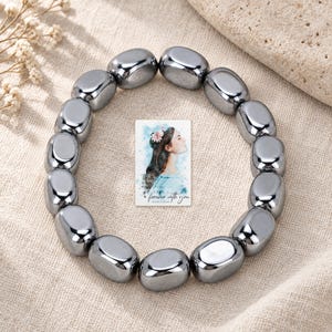 Metallic Grey Bead Bracelet, linen flatlay view. A personalized digital greeting card is shown alongside.