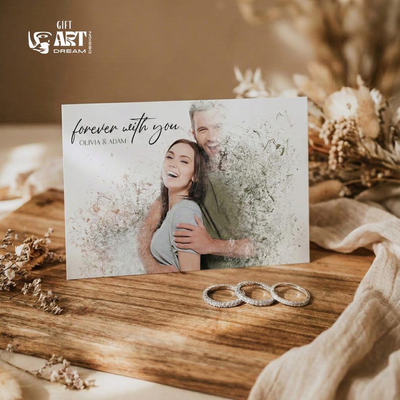 May include: A greeting card with the text "forever with you" and the names Olivia & Adam. The card features a photo of a couple. Three diamond rings are in front of the card on a wooden surface.