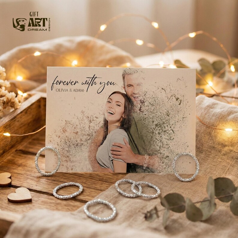 May include: A greeting card with a photo of a couple, the words "forever with you" and the names Olivia & Adam. Several silver rings and wooden hearts are arranged around the card on a wooden tray. Fairy lights are in the background.