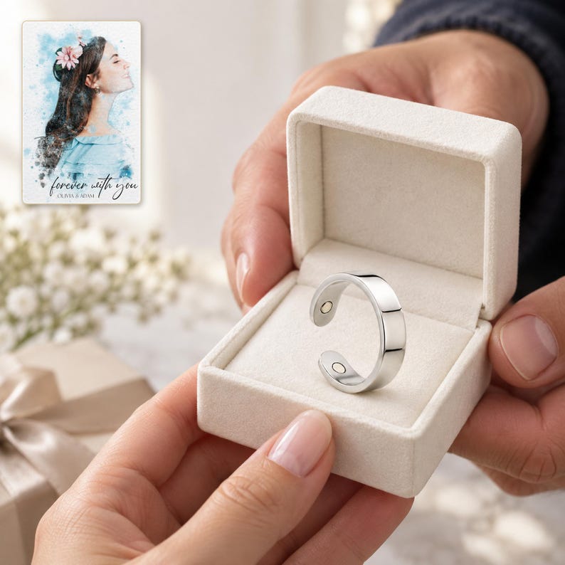 Two adults passing an open ivory box containing one silver-tone open ring, with hands holding only the box edges. A personalized digital greeting card is shown alongside.