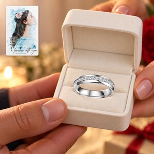 Two adults passing an open ivory box containing one silver-tone single-row clear accents band. A personalized digital greeting card is shown alongside.