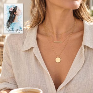 Adult woman wearing all three gold-tone necklaces with a linen blouse at a cafe. A personalized digital greeting card is shown alongside.
