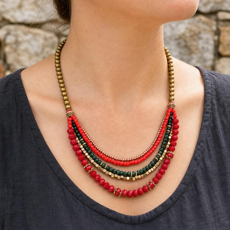 Gift ready presentation of Five strand red deep green copper and antique gold layered beaded statement necklace in an open jewelry box lined with natural ivory linen