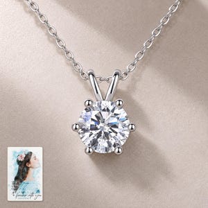 Moissanite Solitaire Necklace, shown on a display surface. A sample personalized digital greeting card is shown alongside.