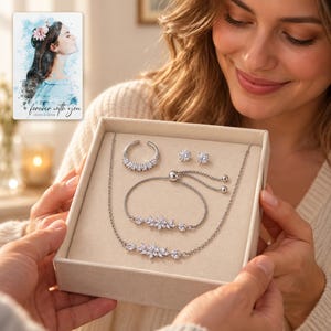 Adult woman receiving the silver-tone floral jewelry suite in an open ivory box. A personalized digital greeting card is shown alongside.