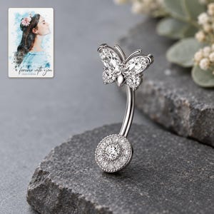 Side view of the butterfly navel bar on matte graphite, showing the curved shaft and setting depth. A personalized digital greeting card is shown alongside.