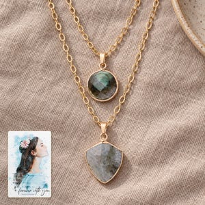Layered Shield Necklace, linen flatlay view. A personalized digital greeting card is shown alongside.