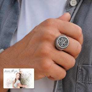 Silver-tone ring with a round tree motif, worn view. A personalized greeting-card example appears in the corner.
