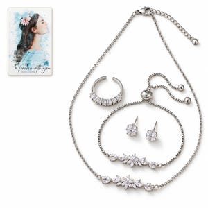 White-background catalog view of the floral necklace and bracelet with an open baguette-front ring and a pair of clear solitaire stud earrings. A personalized digital greeting card is shown alongside.