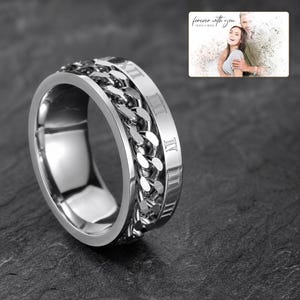 CipherSpin Roman Chain Ring shown during a warm gift-receiving moment between adults with the exact jewelry visible.